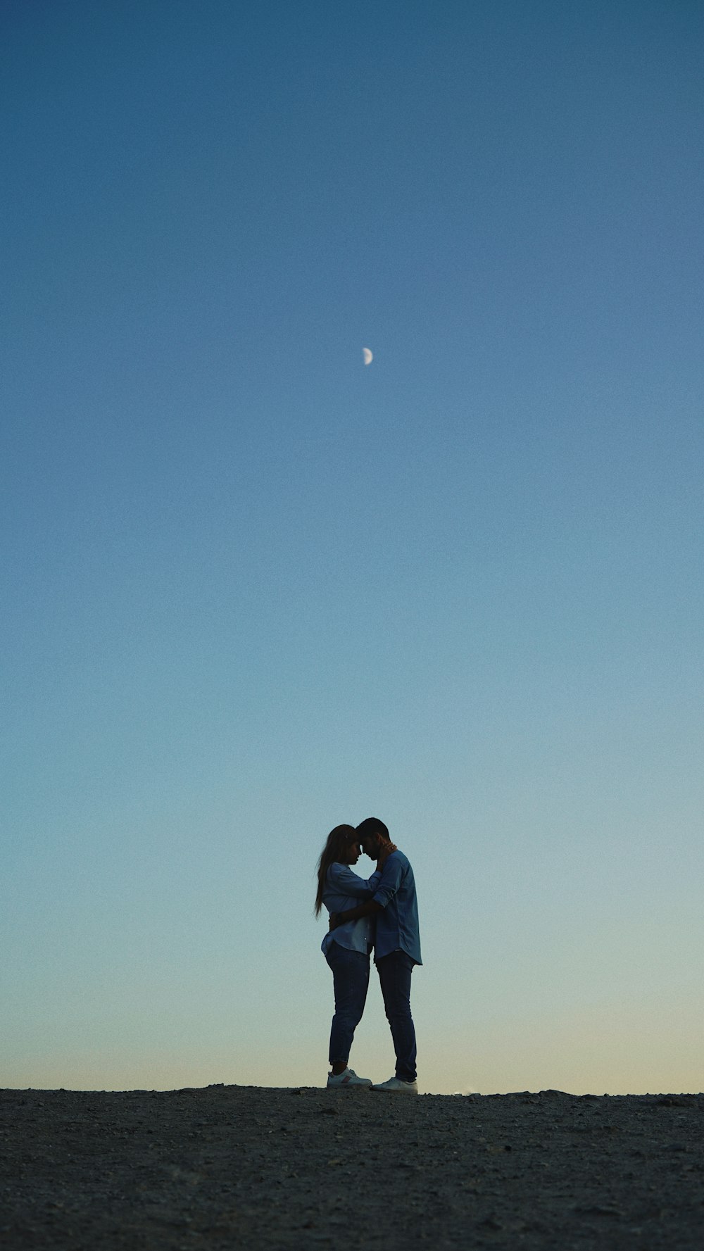 a couple kissing on the beach under a blue sky