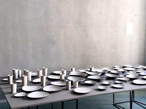 A set of contemporary ceramic plates and mugs arranged on a clean, white table.