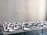 A table is covered with an arrangement of white ceramic dishes and cups of various shapes and sizes, set against a light gray textured wall.