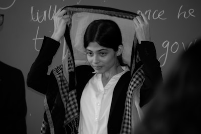 Detail of hands adjusting a patterned scarf over a crisp white shirt.