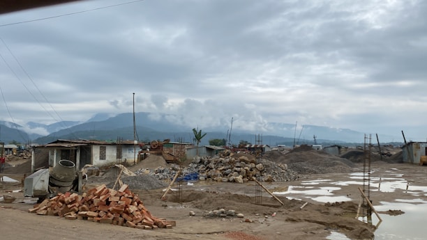 A variety of construction materials including bricks, cement bags, and gravel piles.