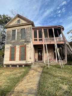 A two-story house with boarded windows and a sagging porch roof.