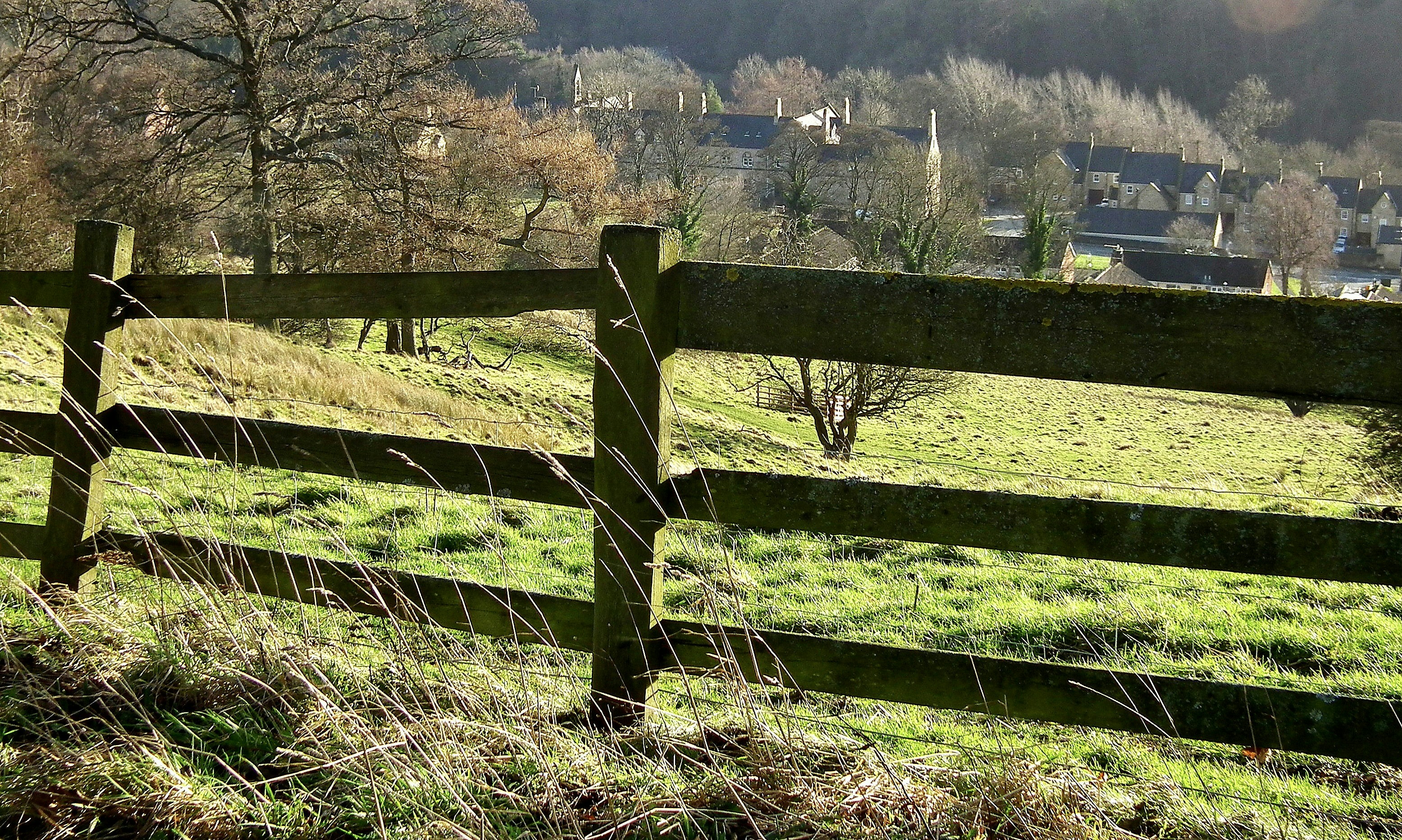 a wooden fence in the middle of a grassy field