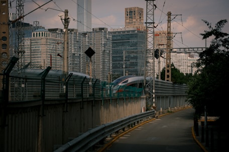 A sleek modern train gliding through a bustling urban landscape at sunset.
