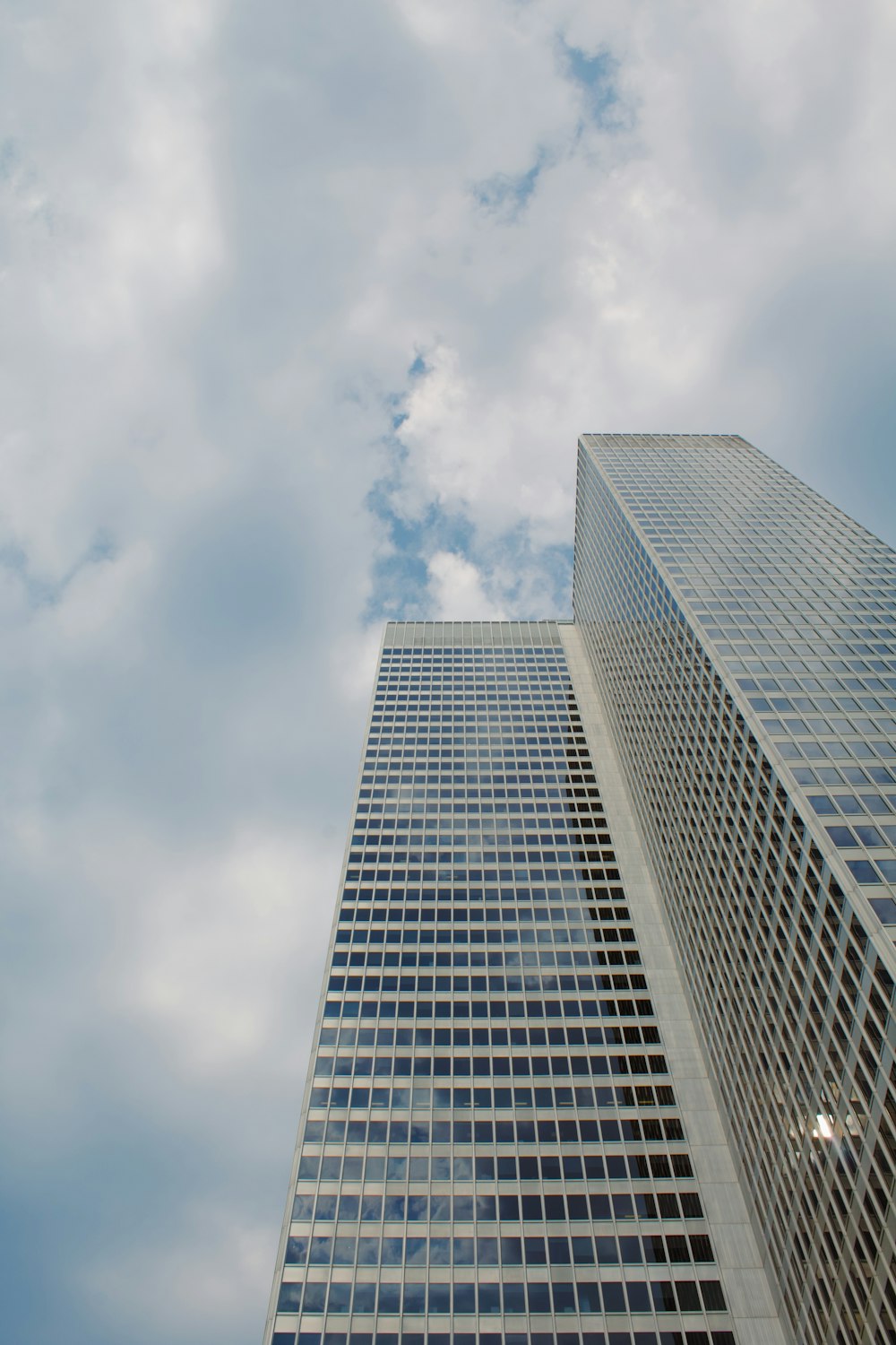 two tall buildings against a cloudy blue sky