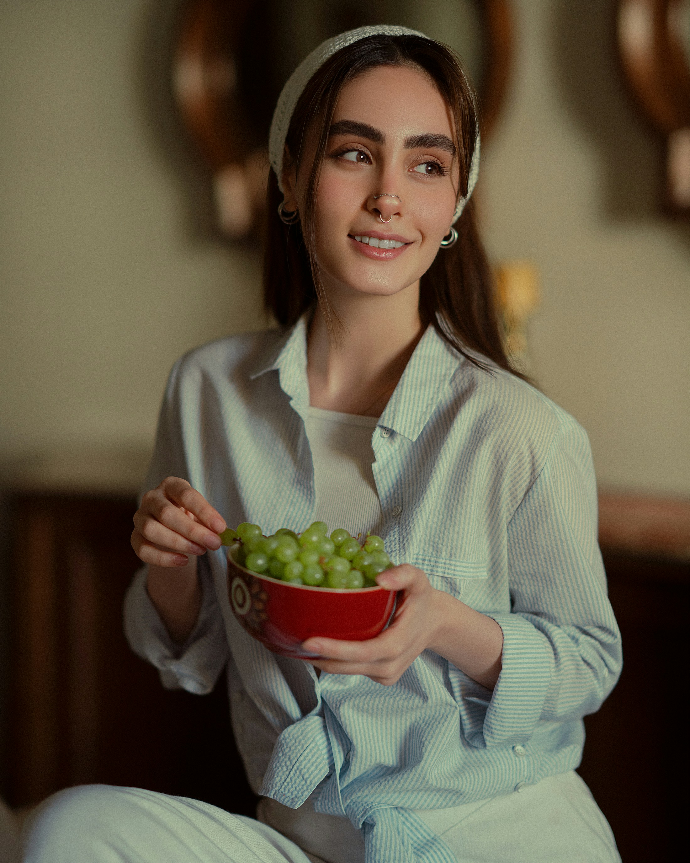 a woman sitting on a bed holding a bowl of grapes