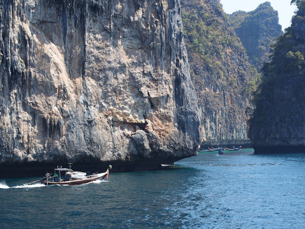 a boat traveling through a body of water near a mountain