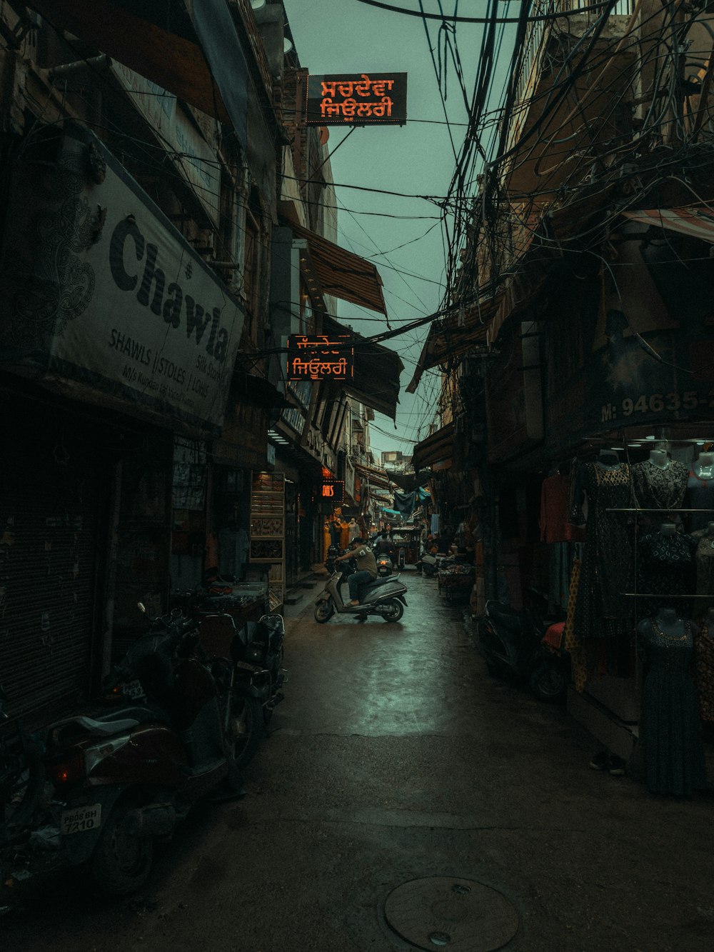 a narrow alleyway with a neon sign above it