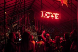 a group of people standing under a neon sign