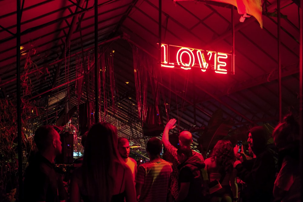 a group of people standing under a neon sign