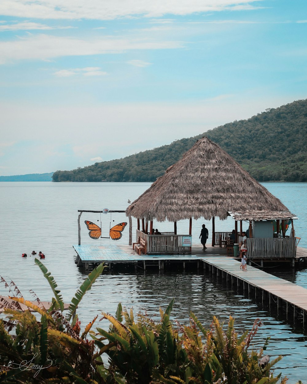 a pier with a thatched roof and a butterfly on it