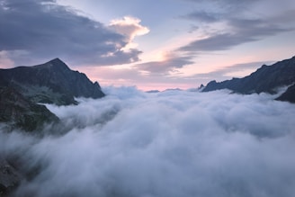 Expansive panorama of a sea of clouds flowing over mountain peaks at dawn