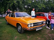 A group of retro car enthusiasts gathered around a restored Audi from the 80s.