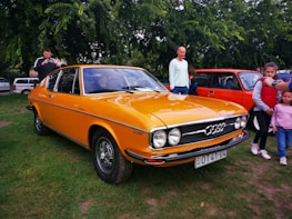 A group of retro car enthusiasts gathered around a restored Audi from the 80s.