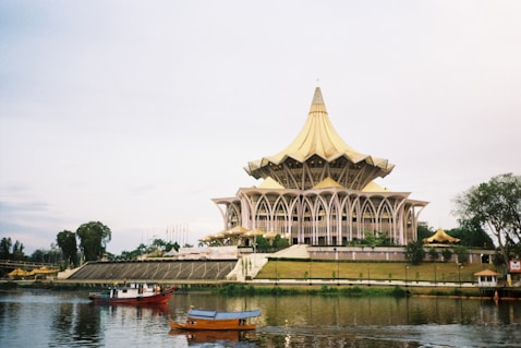 a large building sitting on top of a lake next to a forest