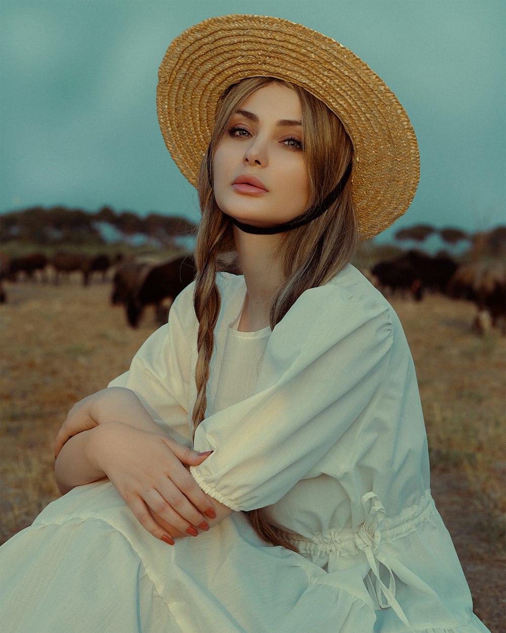 野原に座る麦わら帽子をかぶった女性