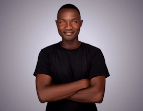 A black man with his arms crossed looking at the camera