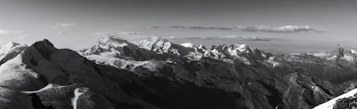 A panoramic view of a snow-capped mountain range with a clear sky, inviting exploration and awe.