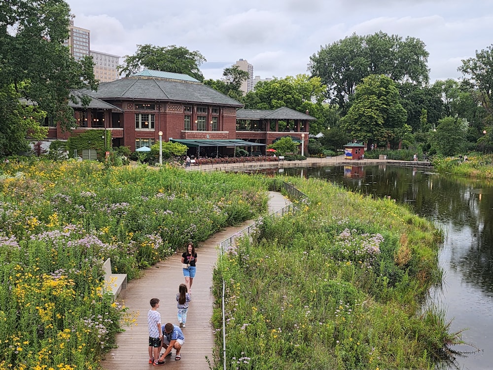 a group of people walking down a path next to a river