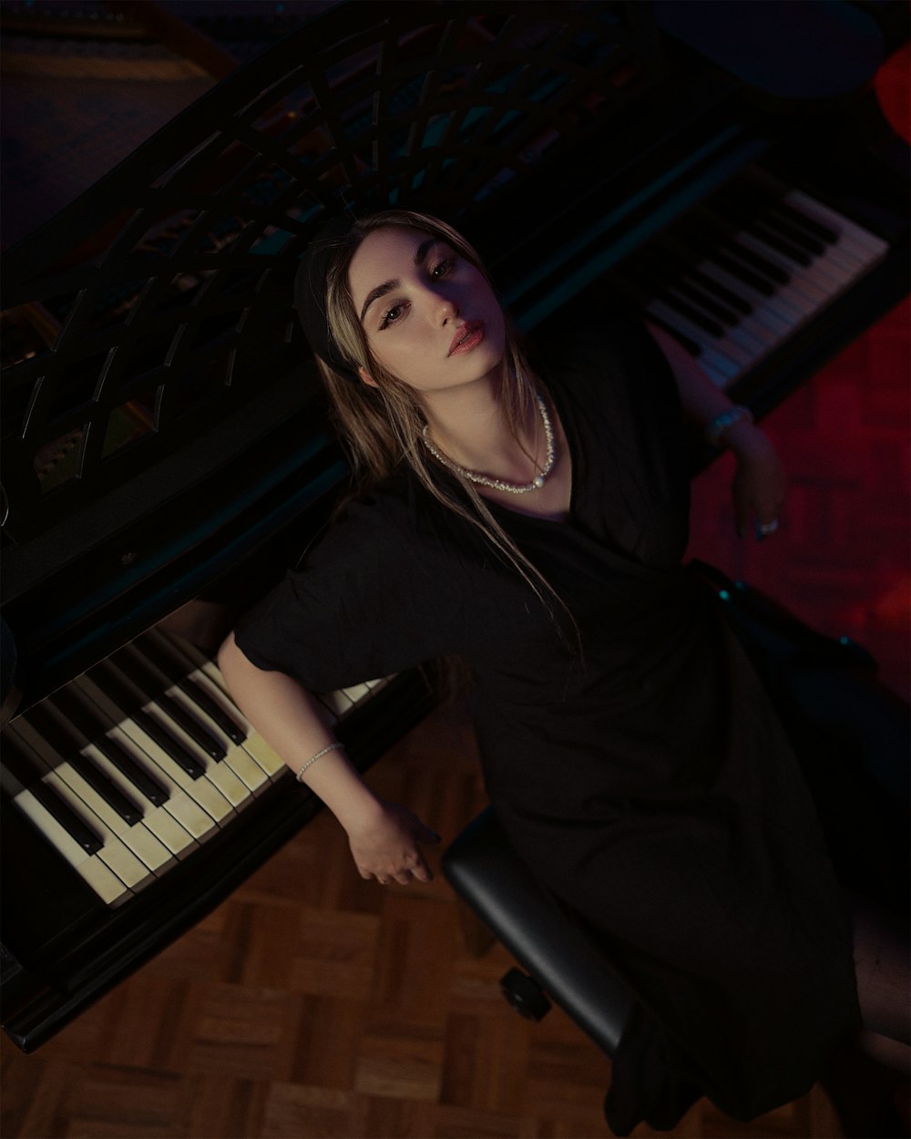 a woman in a black dress sitting at a piano