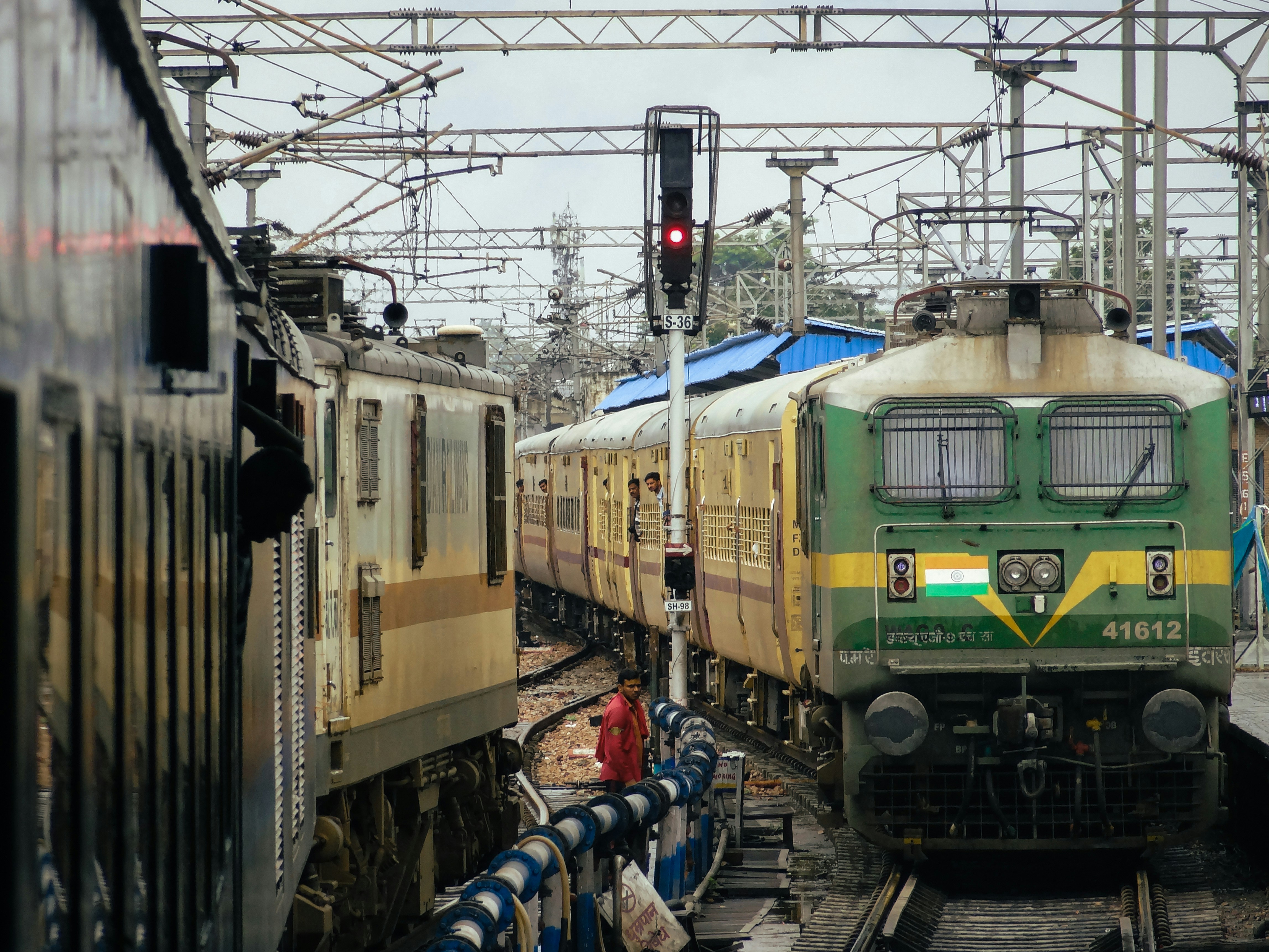 a green and yellow train pulling into a train station, "Busy station scenes" Dehradun Shatabdi with a Ghaziabad WAP7 prepares for departures, as it greets the Nauchandi Express arriving from Prayagraj behind a Itarsi WA9HC.