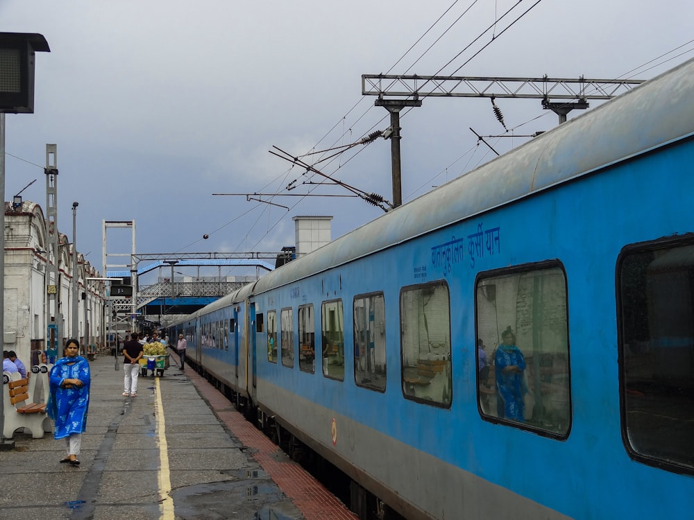 Un tren azul y plateado se detuvo en una estación de tren