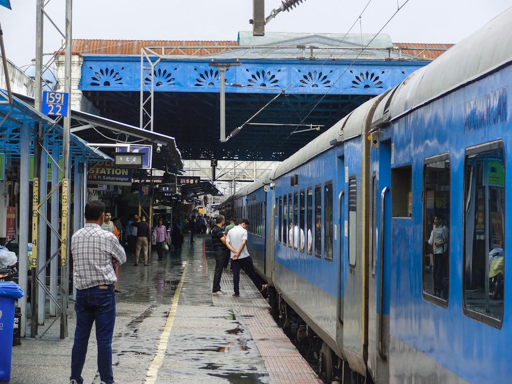 a group of people standing next to a blue train