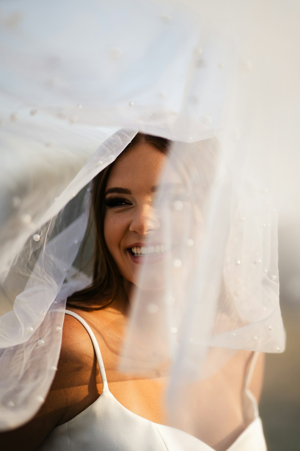 a woman in a white dress and veil smiling