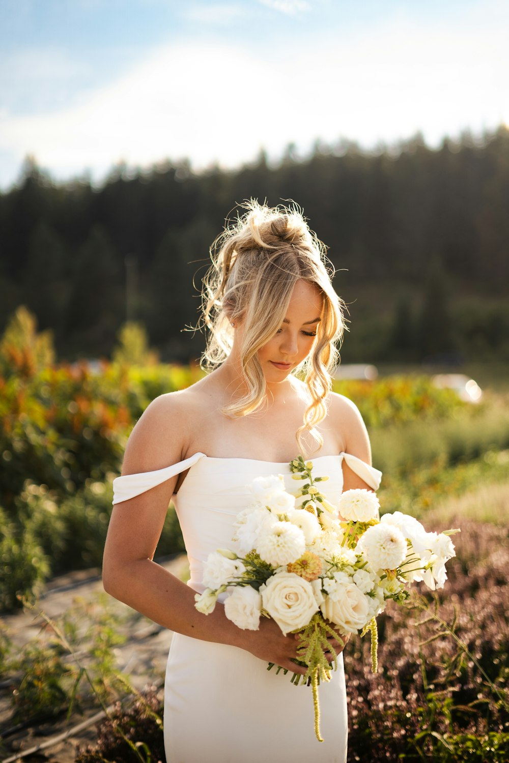 eine Frau in einem weißen Kleid, die einen Blumenstrauß hält