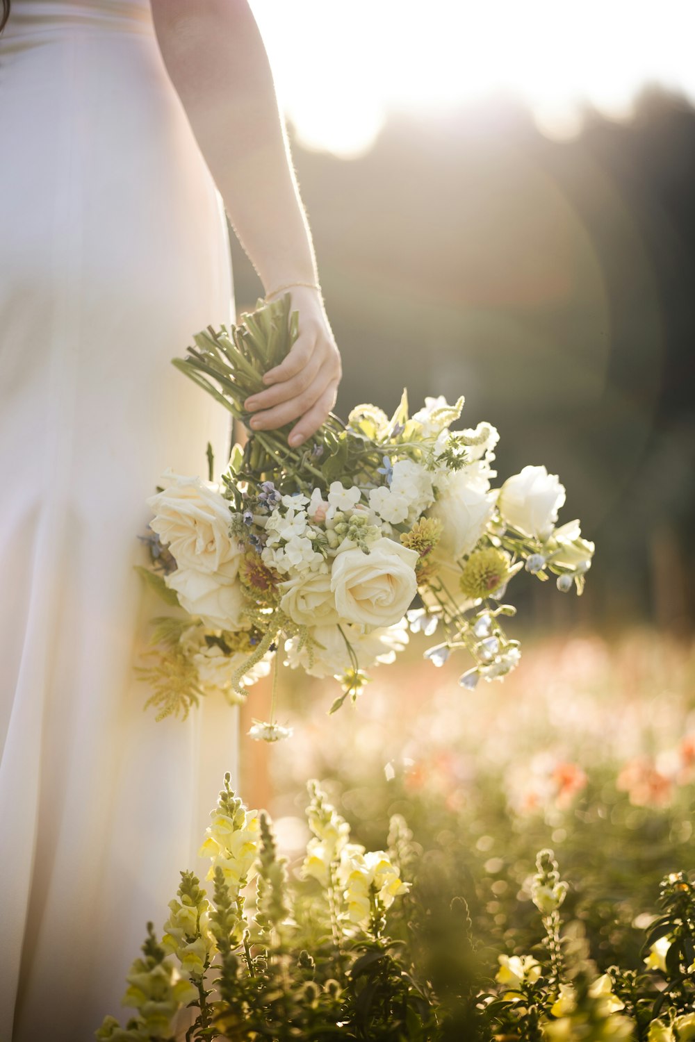 uma noiva segurando um buquê de flores em um campo