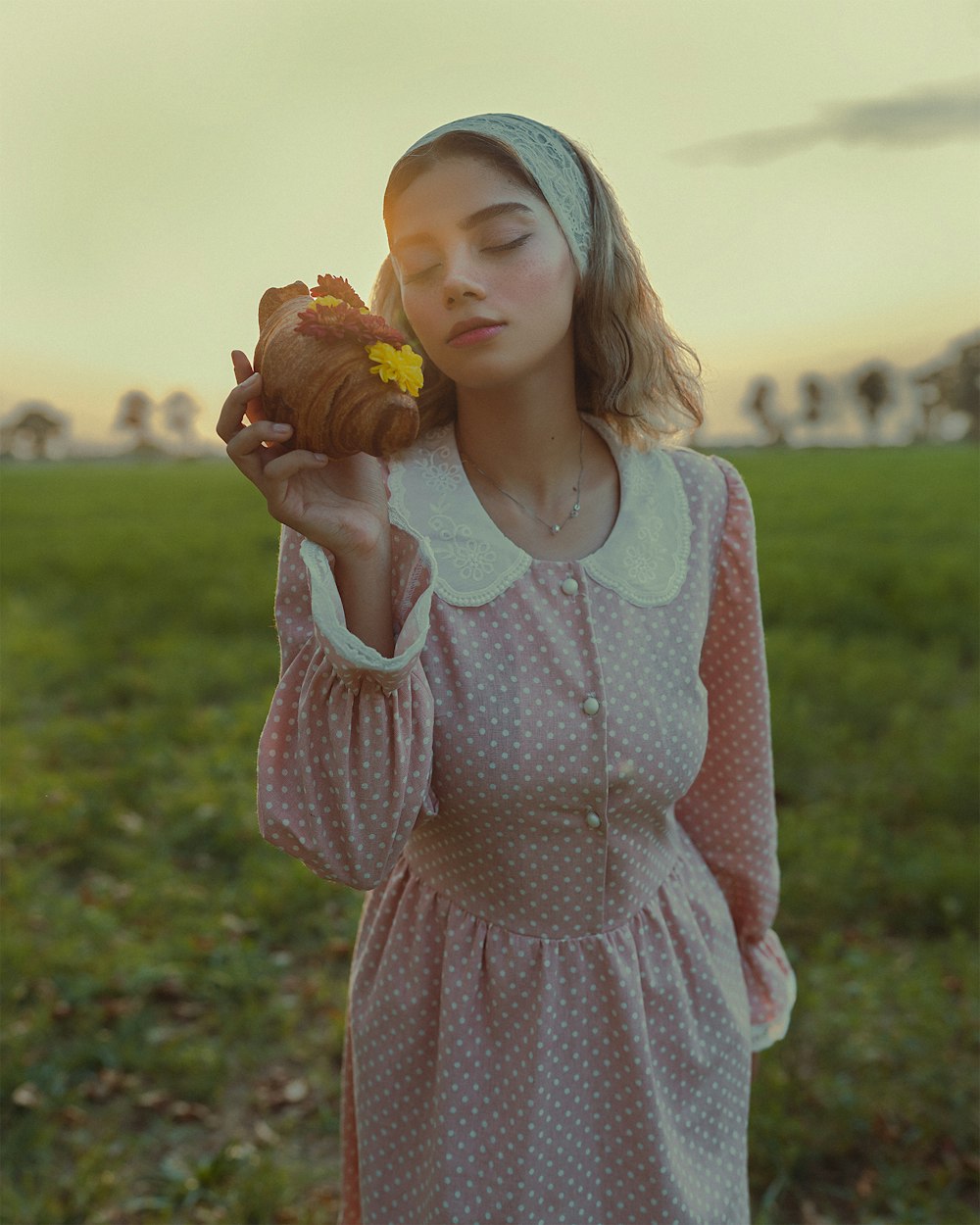 a woman in a pink dress holding a pastry