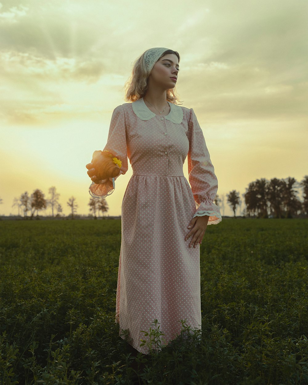 a woman standing in a field holding a teddy bear