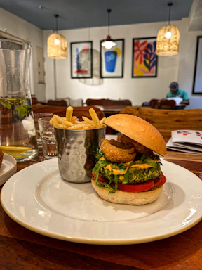 A vibrant plate of classic burger with fries, next to a cold glass of craft beer on a wooden pub table.