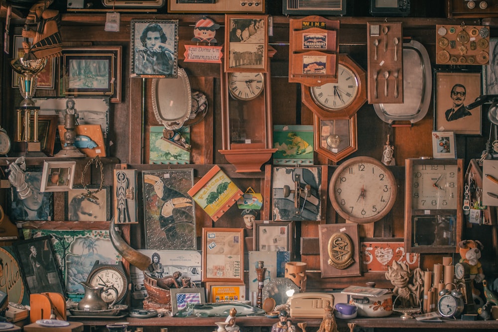 a wall full of clocks and pictures on a shelf