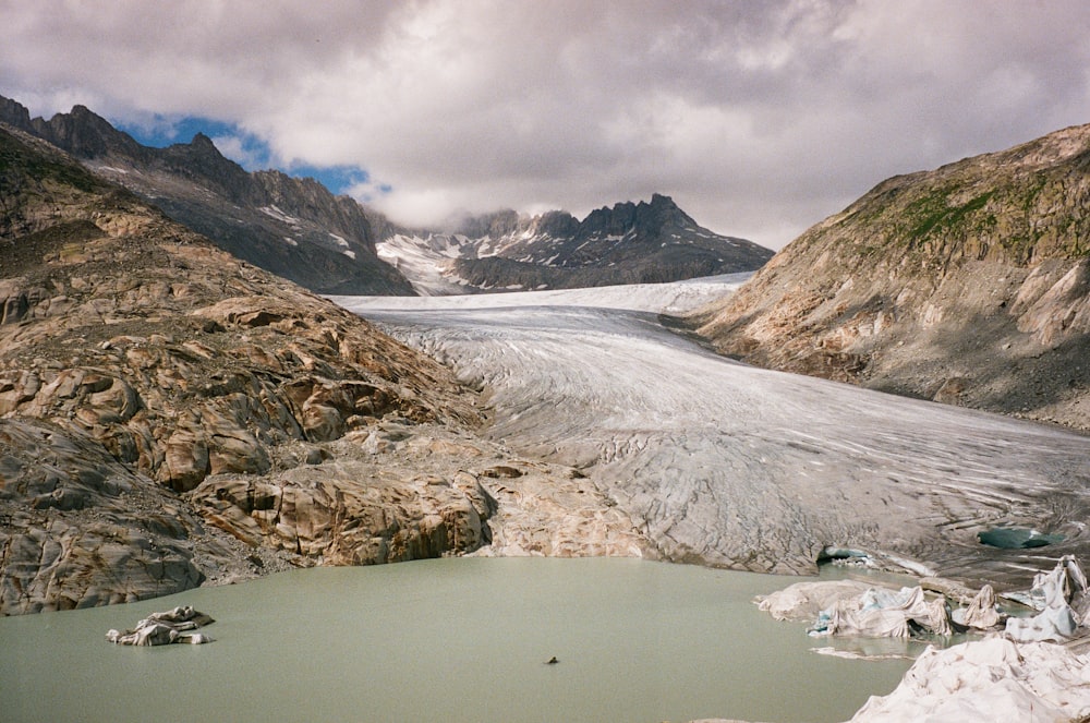 um lago cercado por montanhas sob um céu nublado