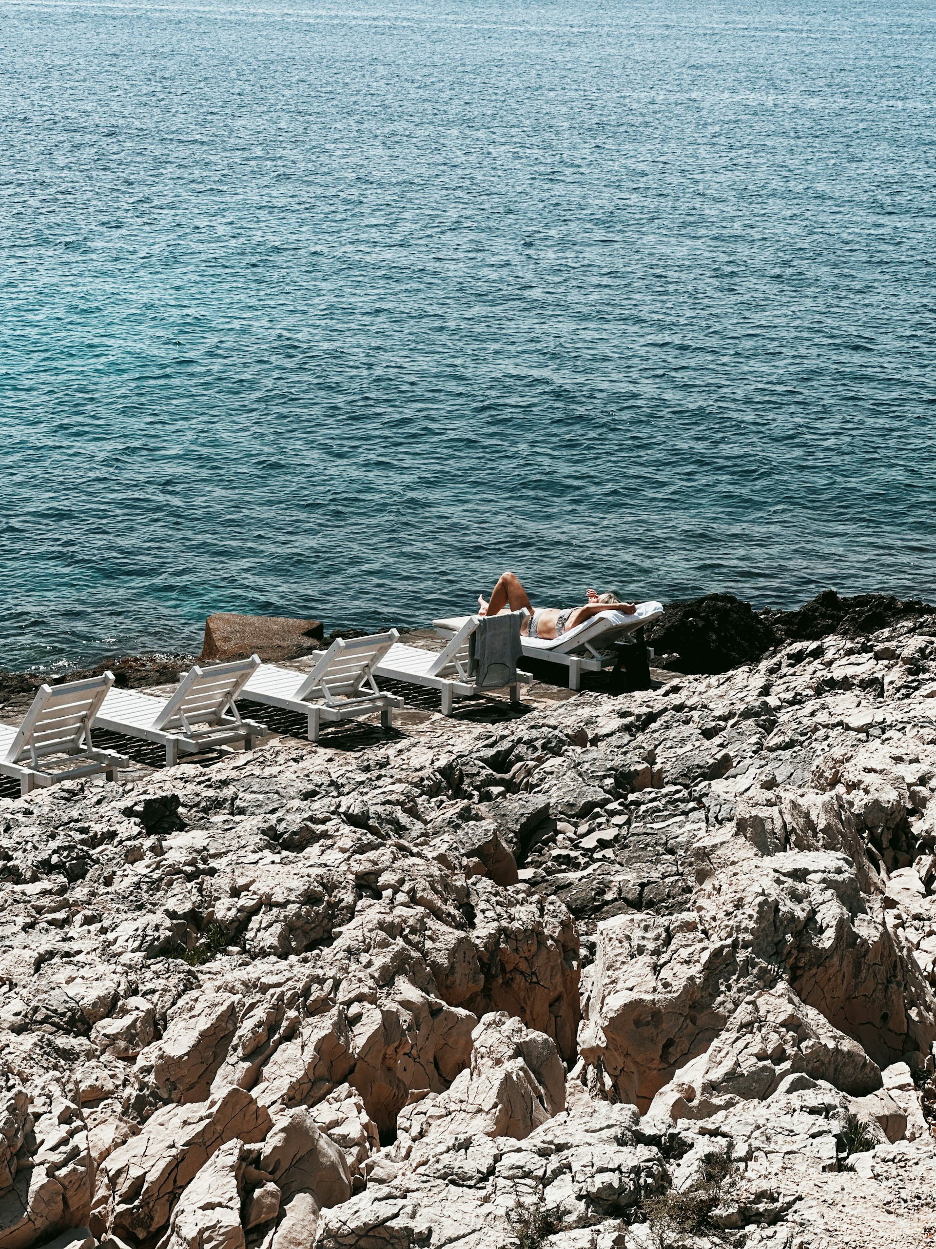a couple of people sitting on top of a rocky beach