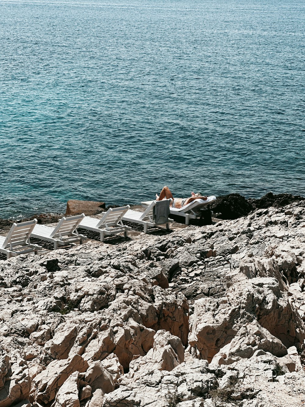 a couple of people sitting on top of a rocky beach