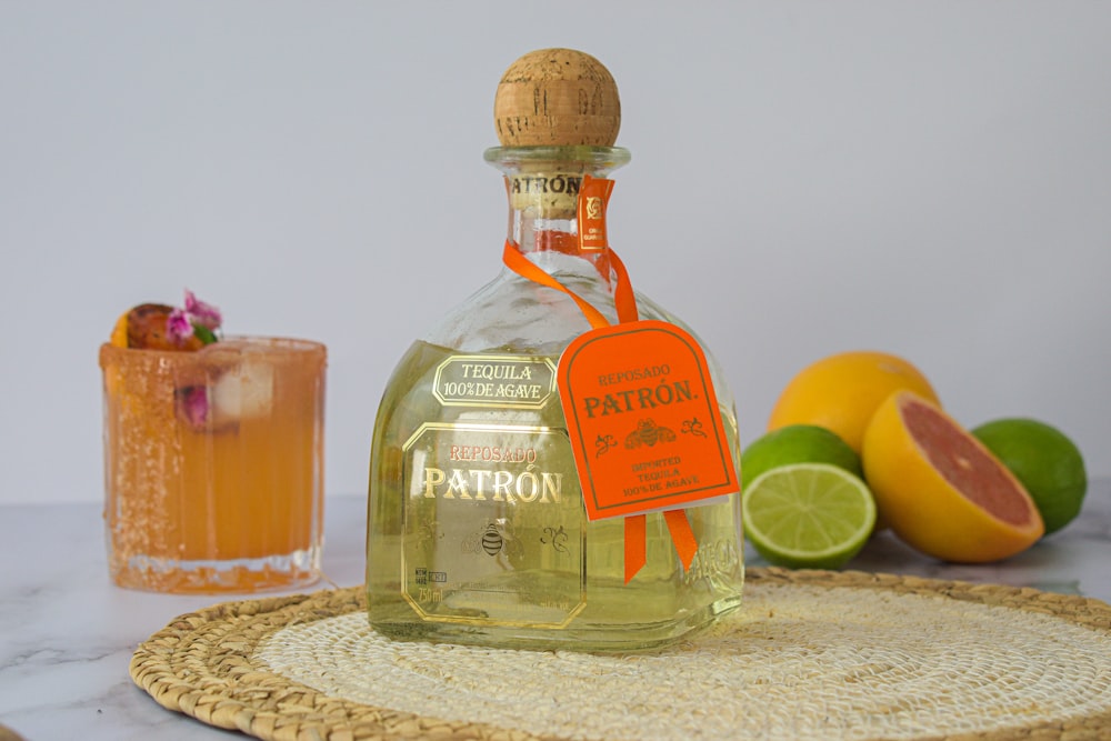 a bottle of patron on a table next to some fruit