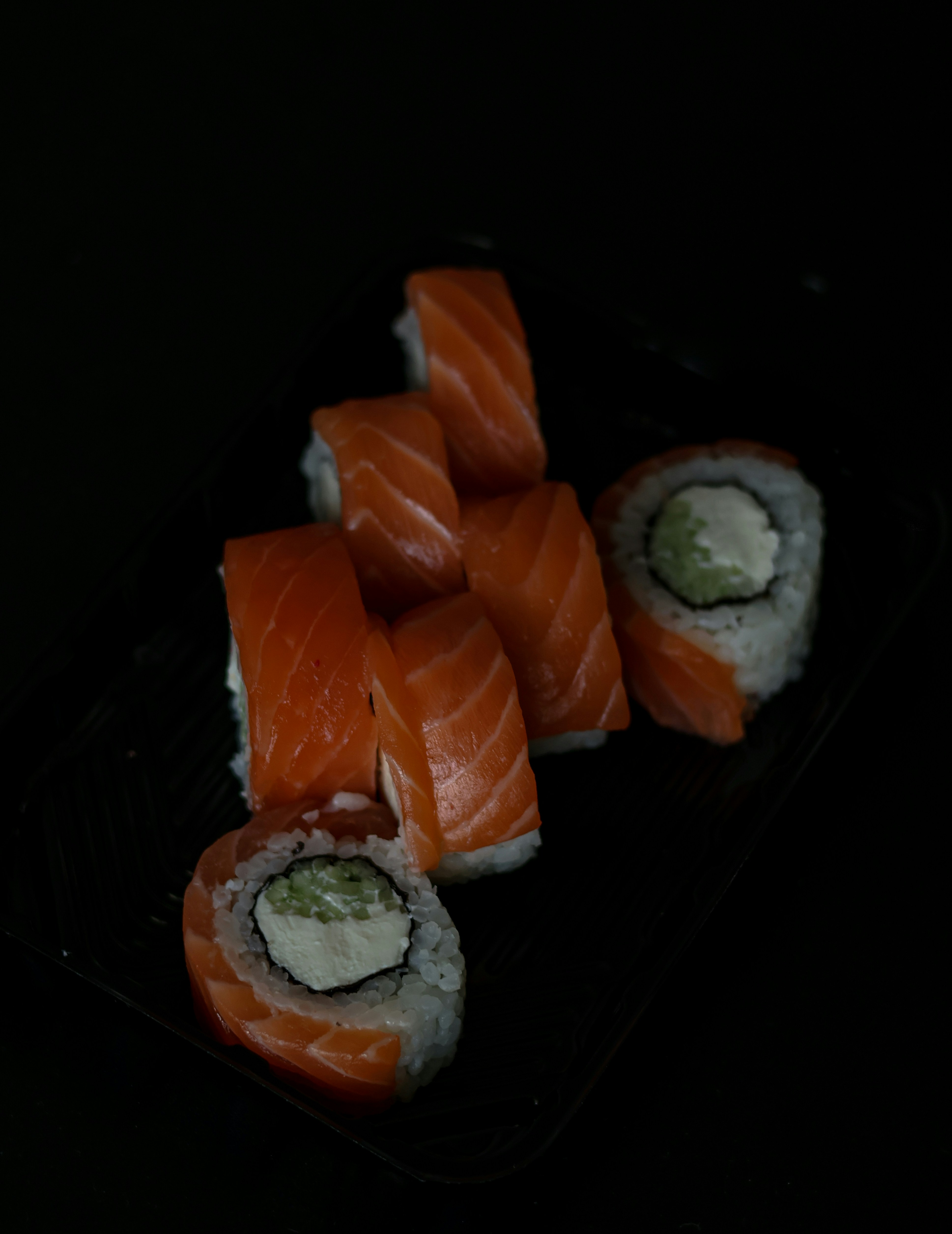 um prato preto coberto com sushi e pepino