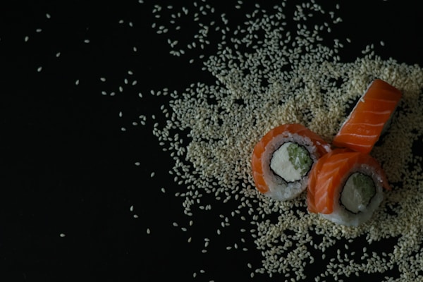 A sushi with sesame seeds on a black background