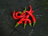 Fresh red chili peppers arranged on a rustic wooden table.