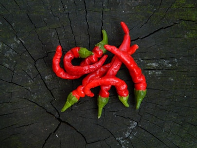 Close-up of vibrant red chili peppers and turmeric roots on rustic wooden table