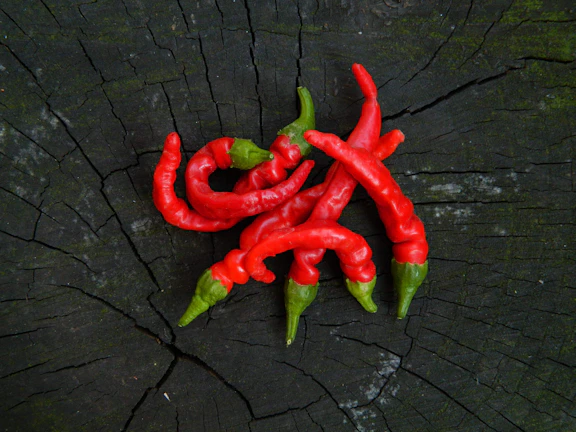 Close-up of vibrant dried chili-covered fruit snacks arranged on rustic wooden table.