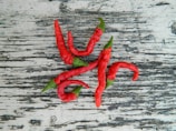Colorful chili peppers drying in the sun on a rustic wooden surface.