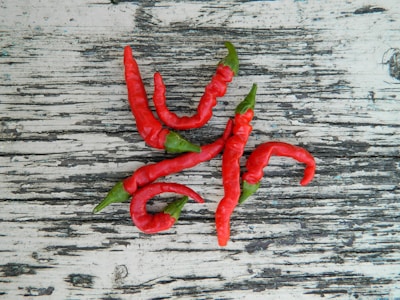 Colorful chili peppers drying in the sun on a rustic wooden surface.