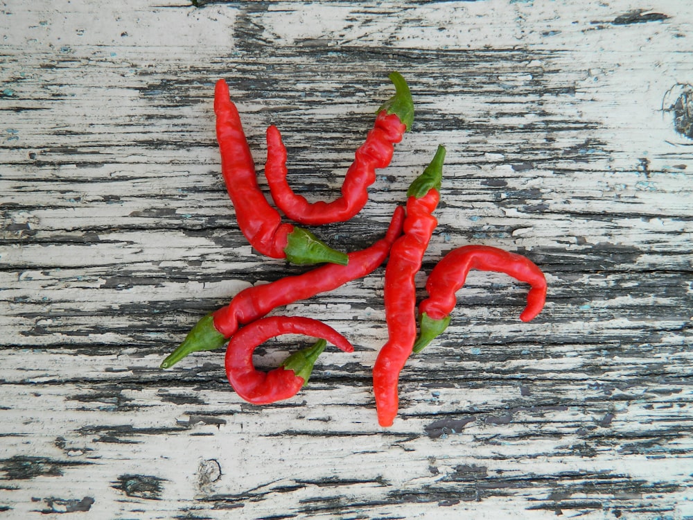 a group of red peppers sitting on top of a wooden table