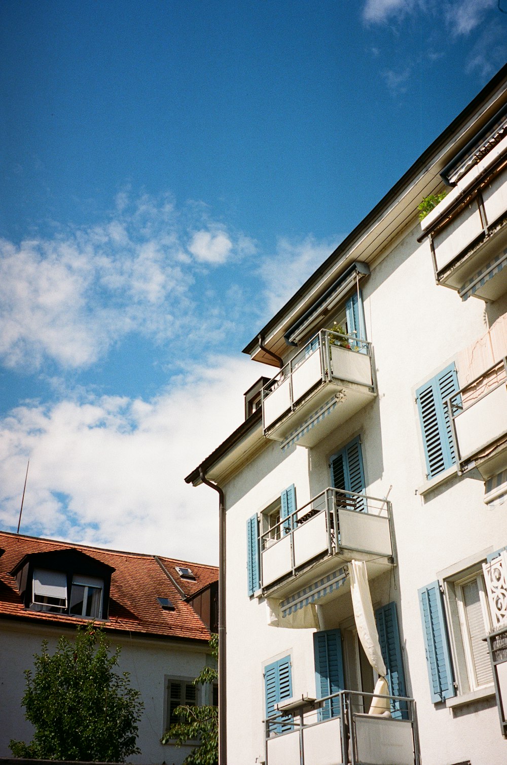 a tall white building with blue shutters and balconies