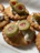 Golden crackers topped with a creamy white spread and garnished with sliced green olives, each featuring a pimento stuffing in the center.
