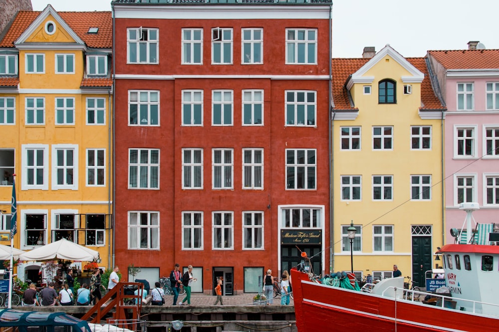 a red boat is in front of a row of colorful buildings
