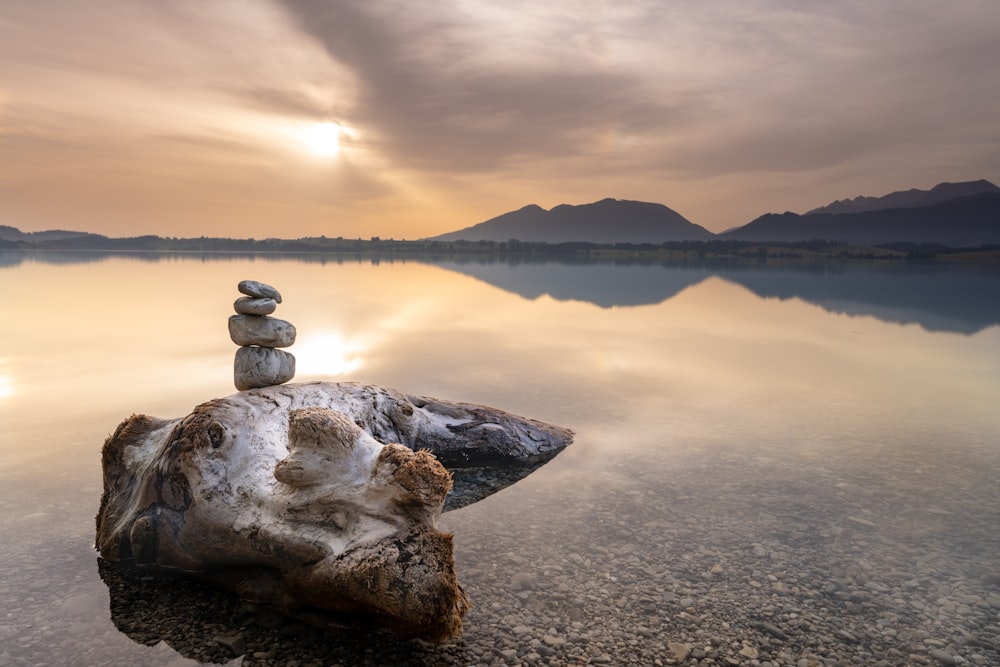 a stack of rocks sitting on top of a rock in the middle of a lake